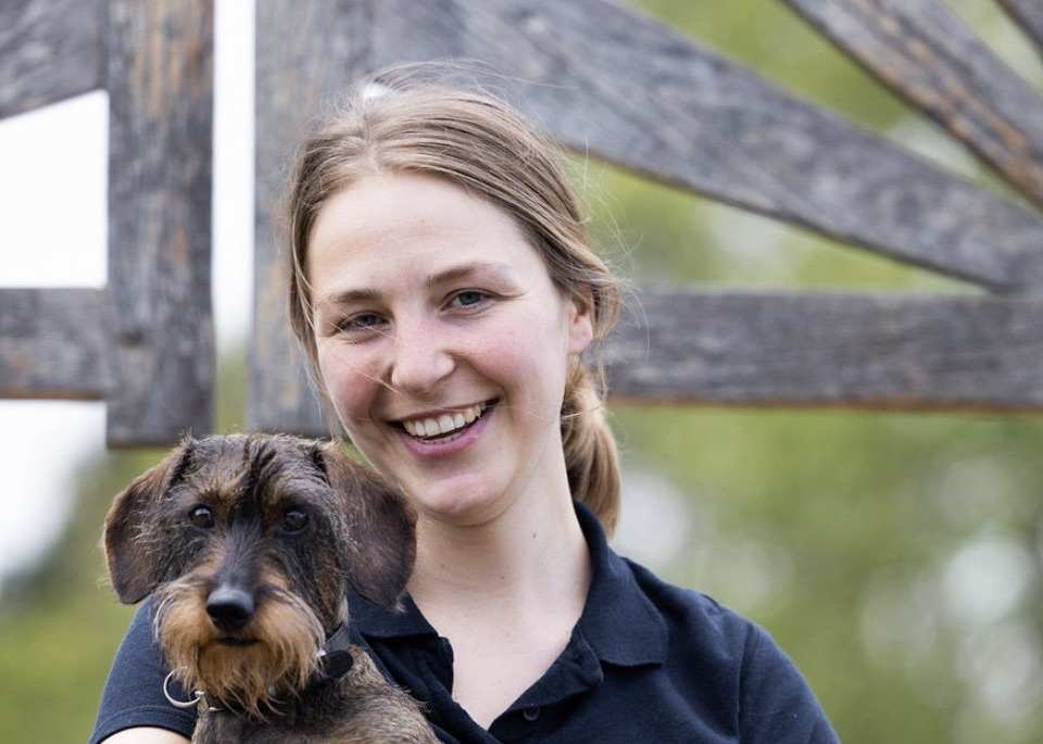 Camille Buyck lachend, met een teckel in de armen
